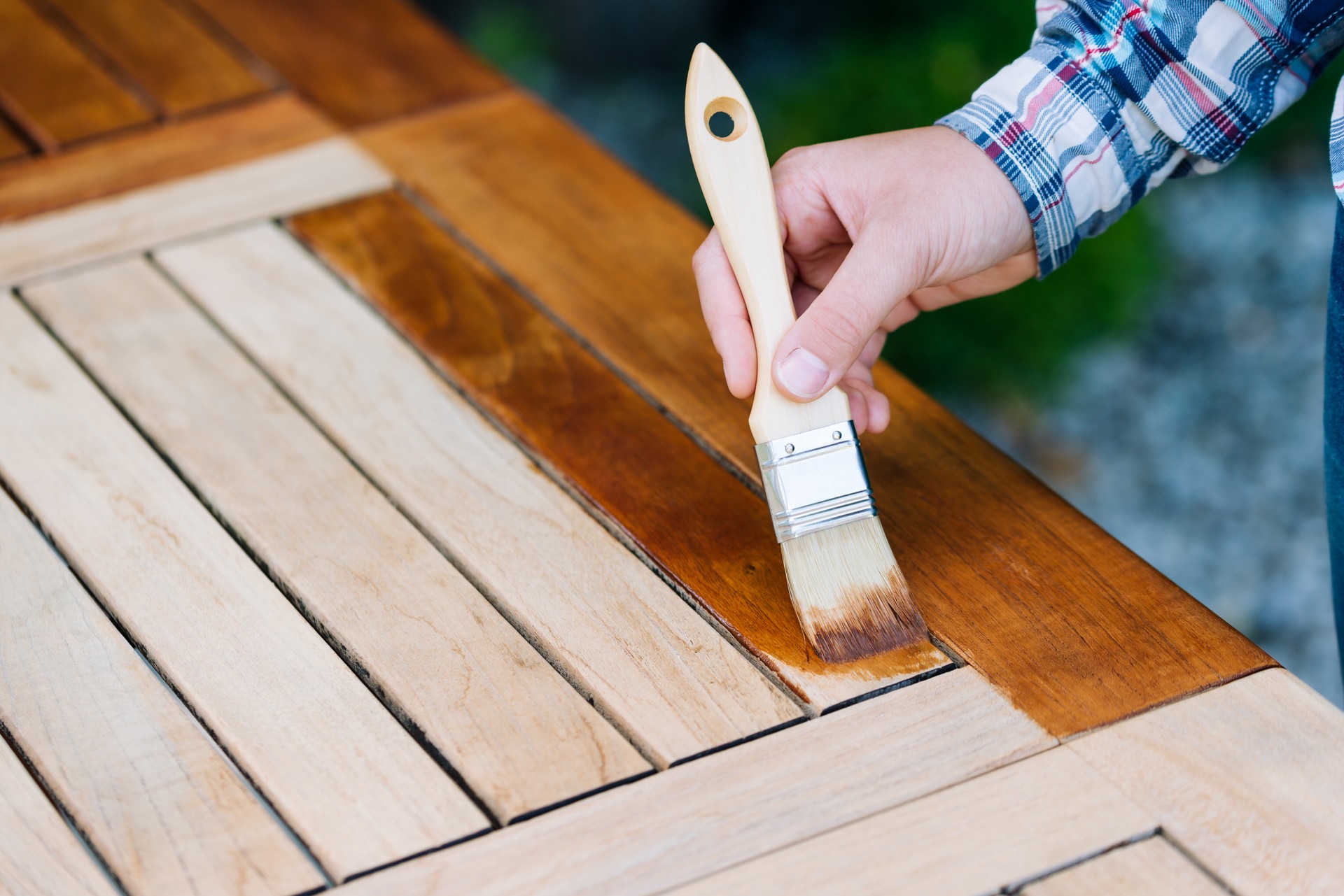 renovation of a garden table with a brush and oil by a young woman on the terrace