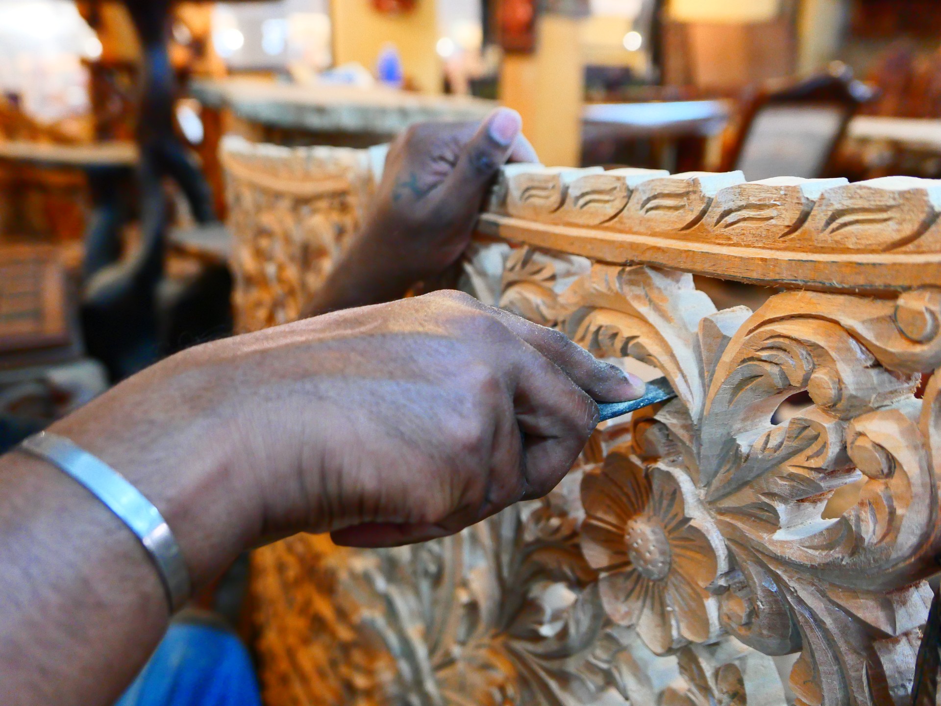 A wood carver carving out a flower leaf design